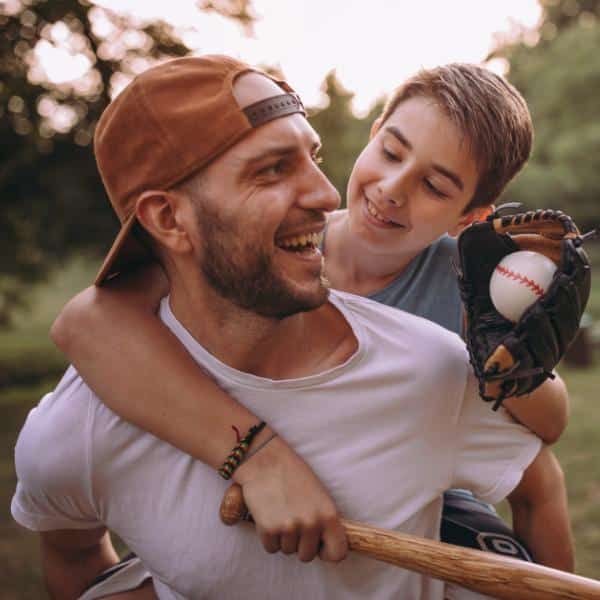 A father and a son with a baseball bat, baseball and glove.