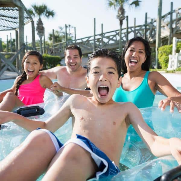 A father, mother, son, and daughter having fun on a lazy river at a water park.